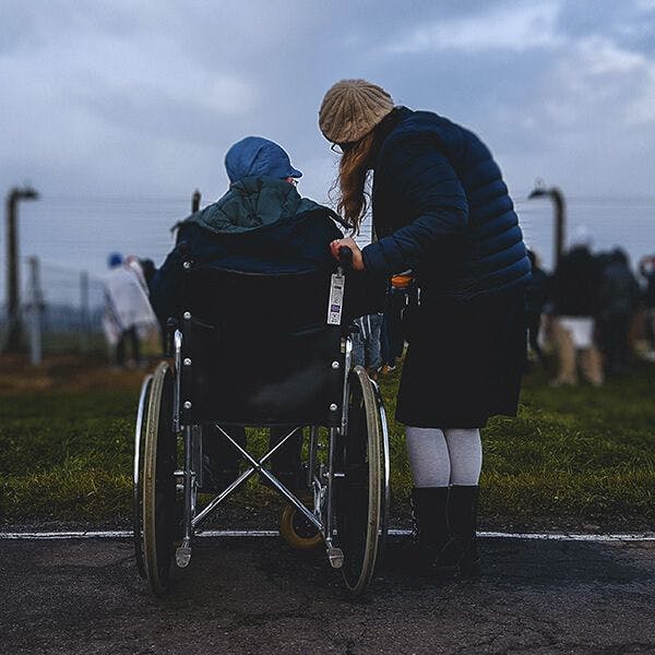 Cuidadora dando un paseo con una persona mayor que va en silla de ruedas