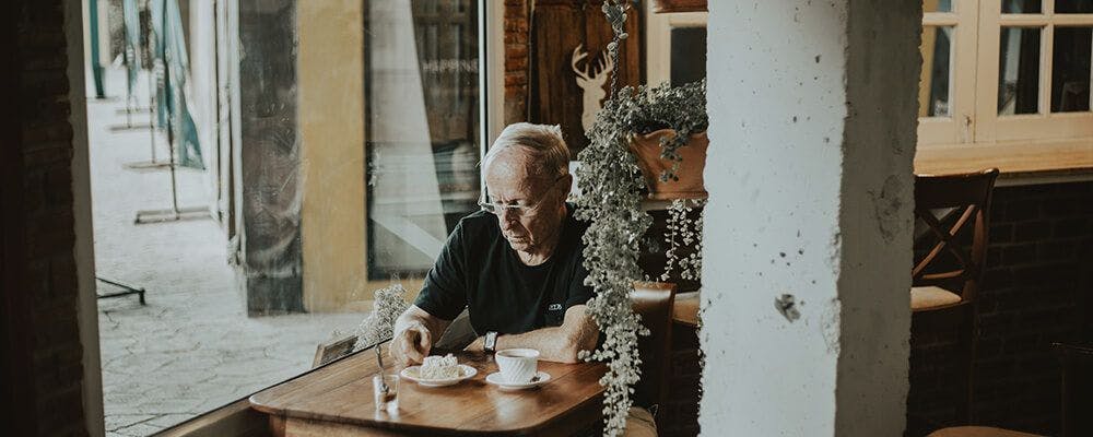 Señor mayor tranquilo escribiendo en una cafetería